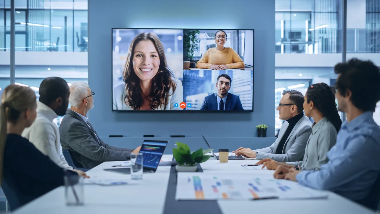 Large modern boardroom with video call on a big screen, professional global meeting