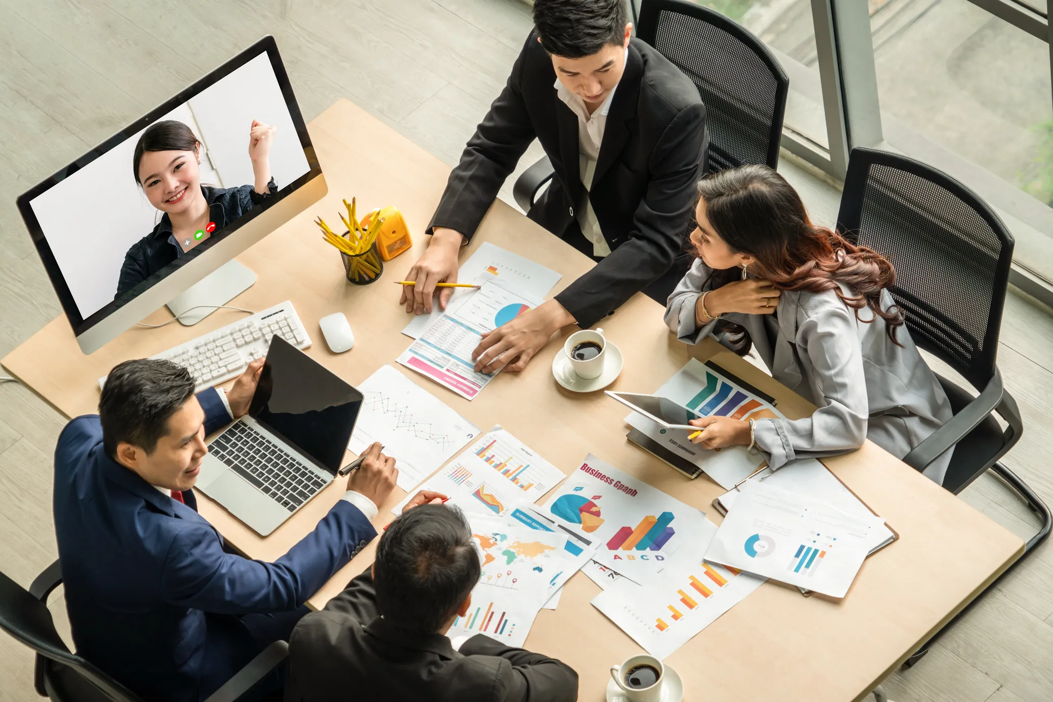 Small team in bright office with remote participant on screen, discussing partnership kick-off